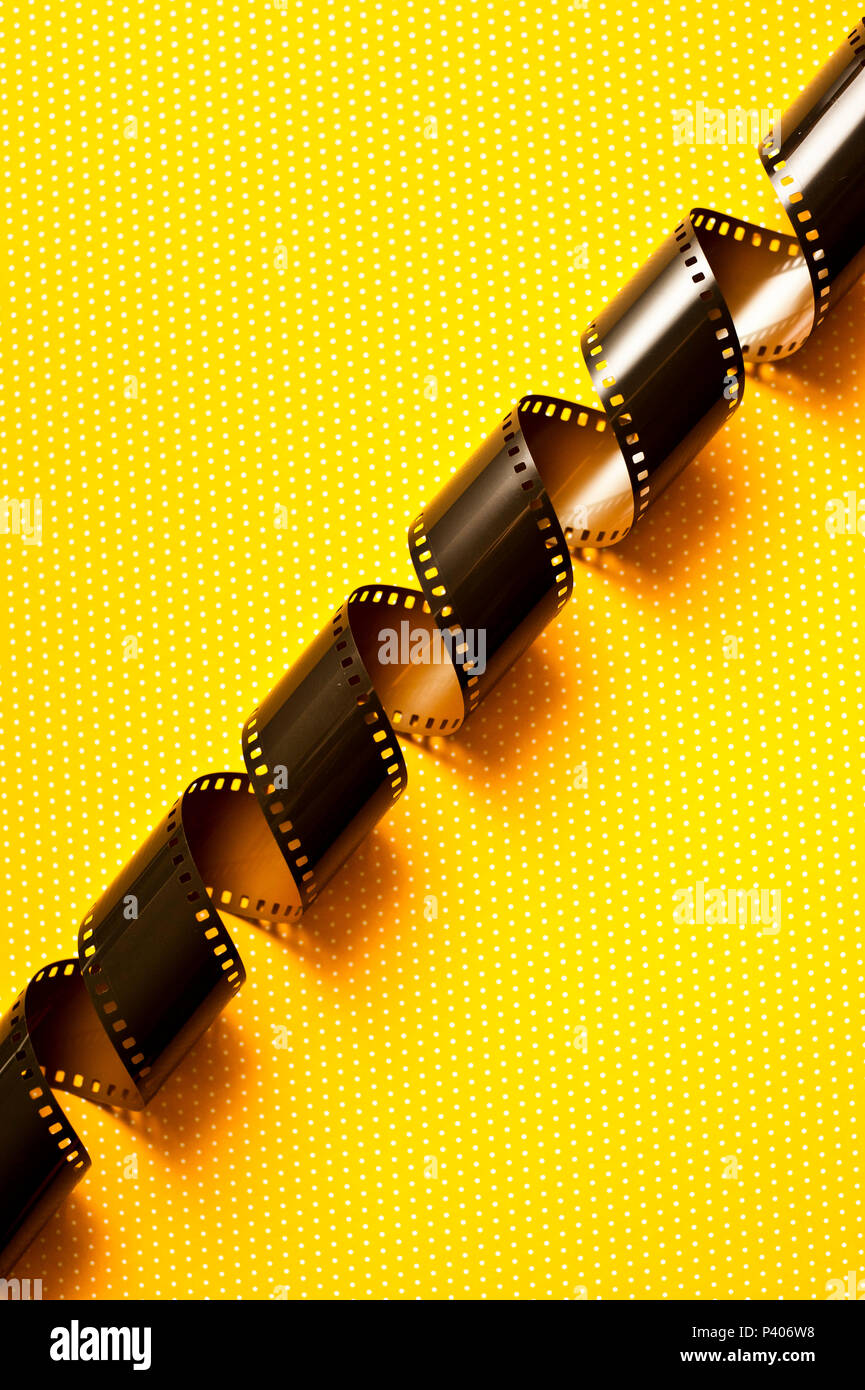 photographic film roll unwrapped on a yellow background Stock Photo