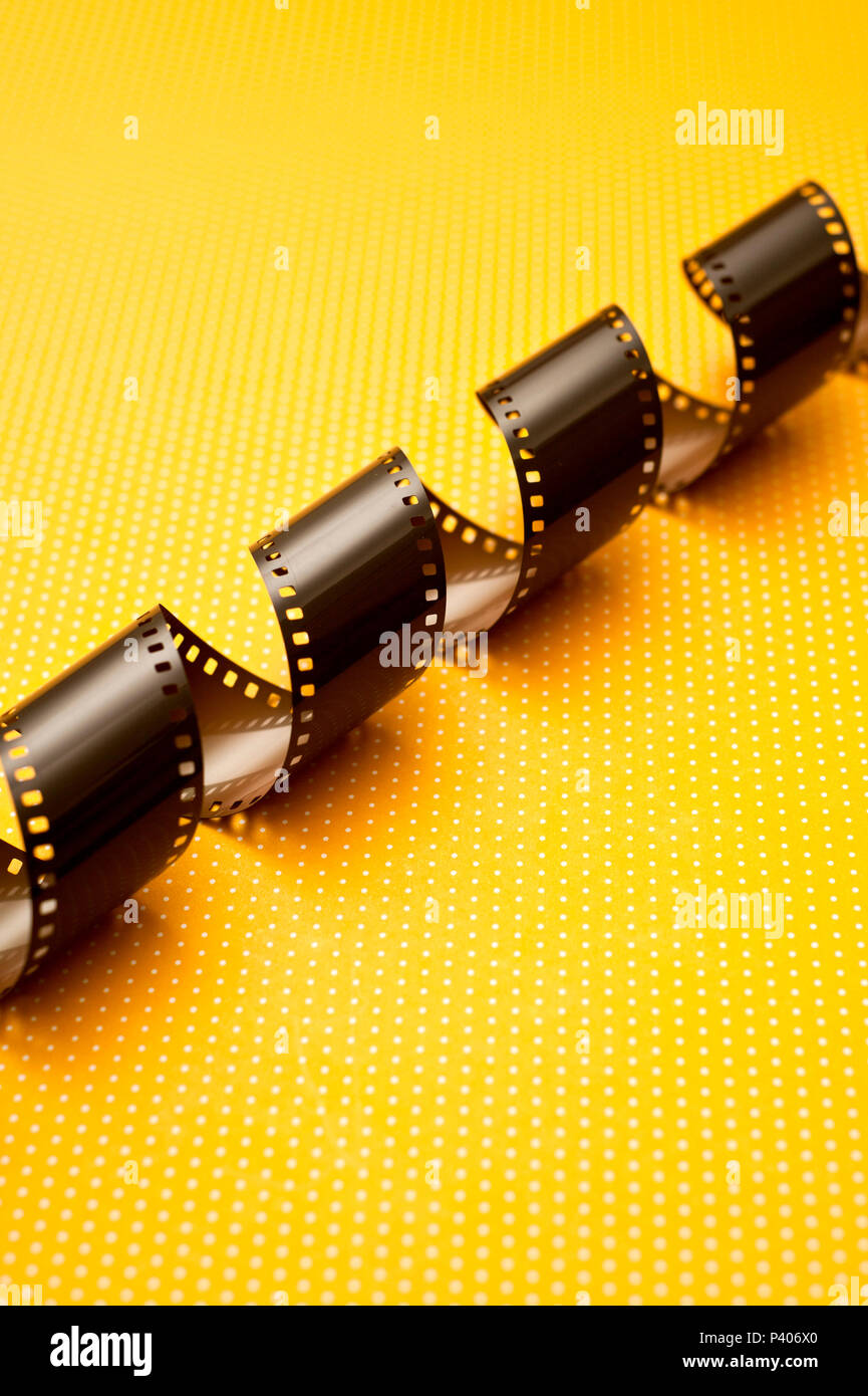 photographic film roll unwrapped on a yellow background Stock Photo