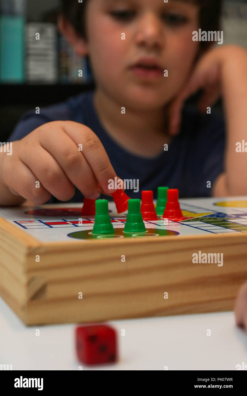 Brincadeiras dentro de casa. Criança jogando Ludo, um clássico dos