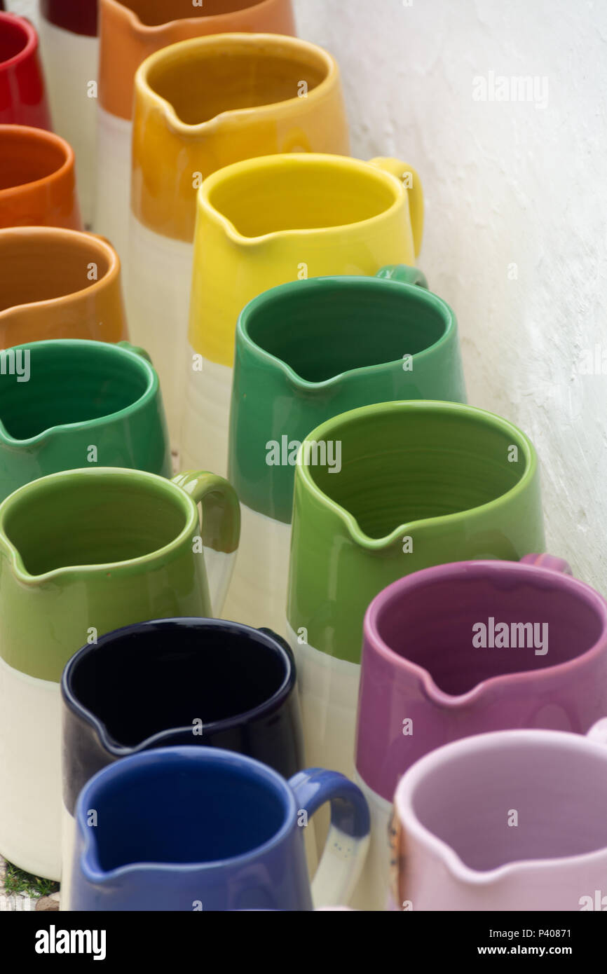 Rows with colorful glazed ceramic jars, flower pots, vases for sale