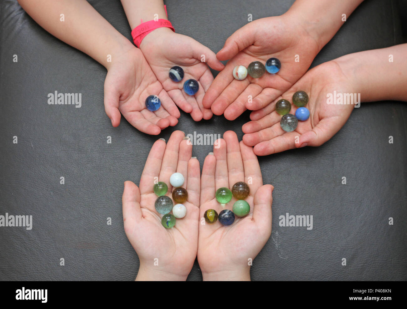 Mãos de crianças contendo bolinhas de gude perfeitamente contáveis. Stock Photo