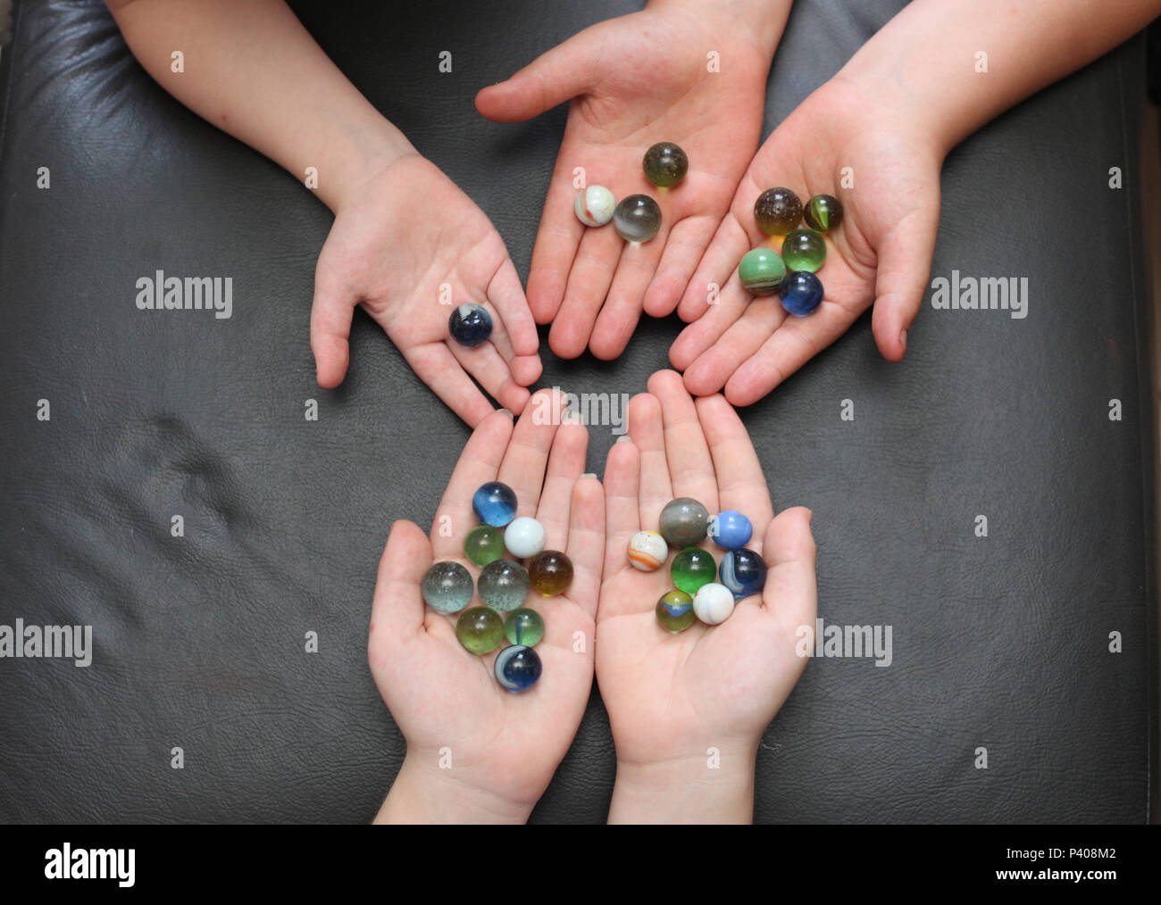 Mãos de crianças contendo bolinhas de gude perfeitamente contáveis. Stock Photo