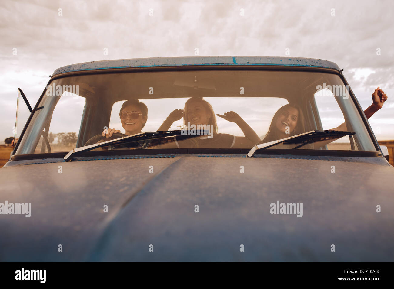 Three young women enjoying in car during vacation. Young female friends having fun on road trip. Stock Photo