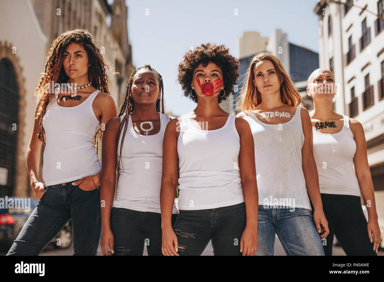 Group of women protesters march on road for women empowerment. Female activists in dress code demonstrating outdoors. Stock Photo