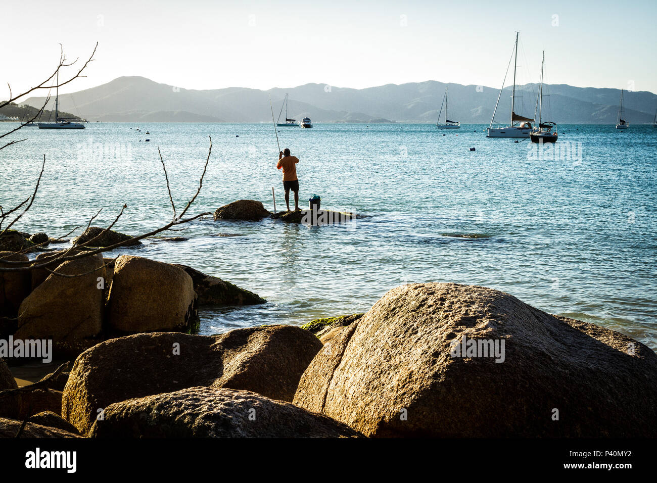 Homem pescando sobre rocha no costão rochoso na Praia de Jurerê. Florianópolis, Santa Catarina, Brasil. Stock Photo