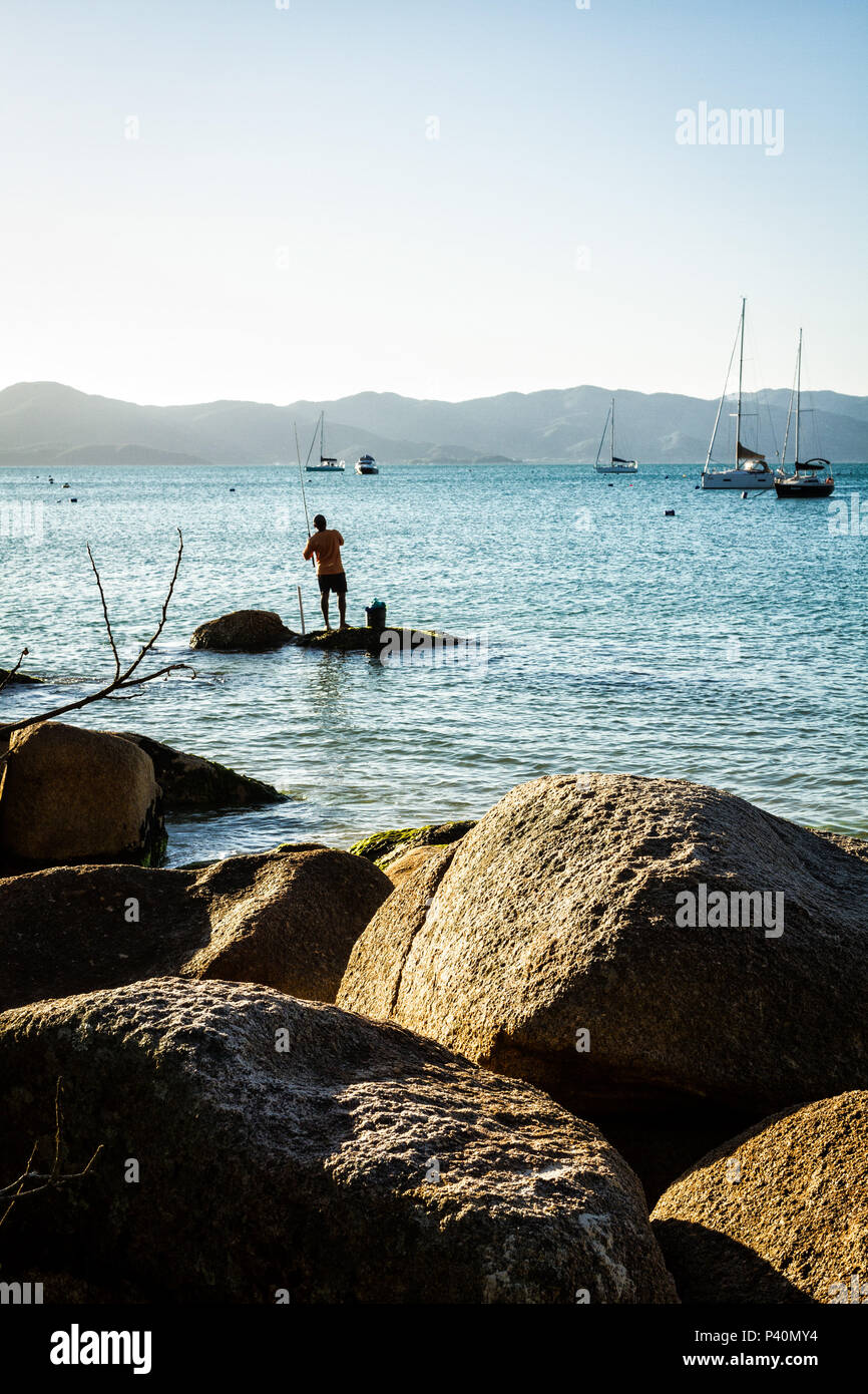 Homem pescando sobre rocha no costão rochoso na Praia de Jurerê. Florianópolis, Santa Catarina, Brasil. Stock Photo