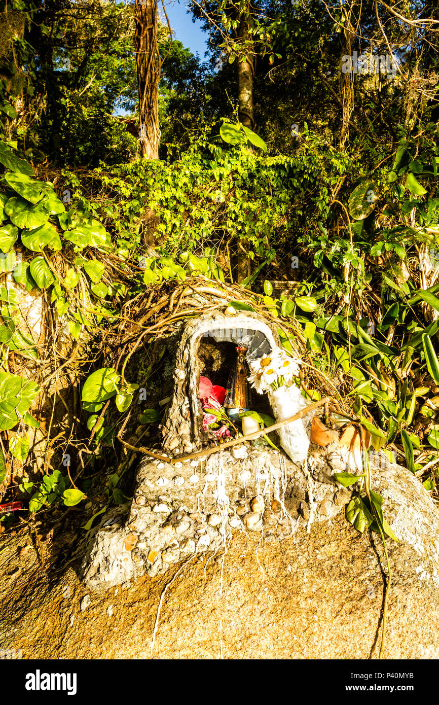 Pequena estátua de Nossa Senhora Aparecida em costão rochoso na Praia de Jurerê. Florianópolis, Santa Catarina, Brasil. Stock Photo