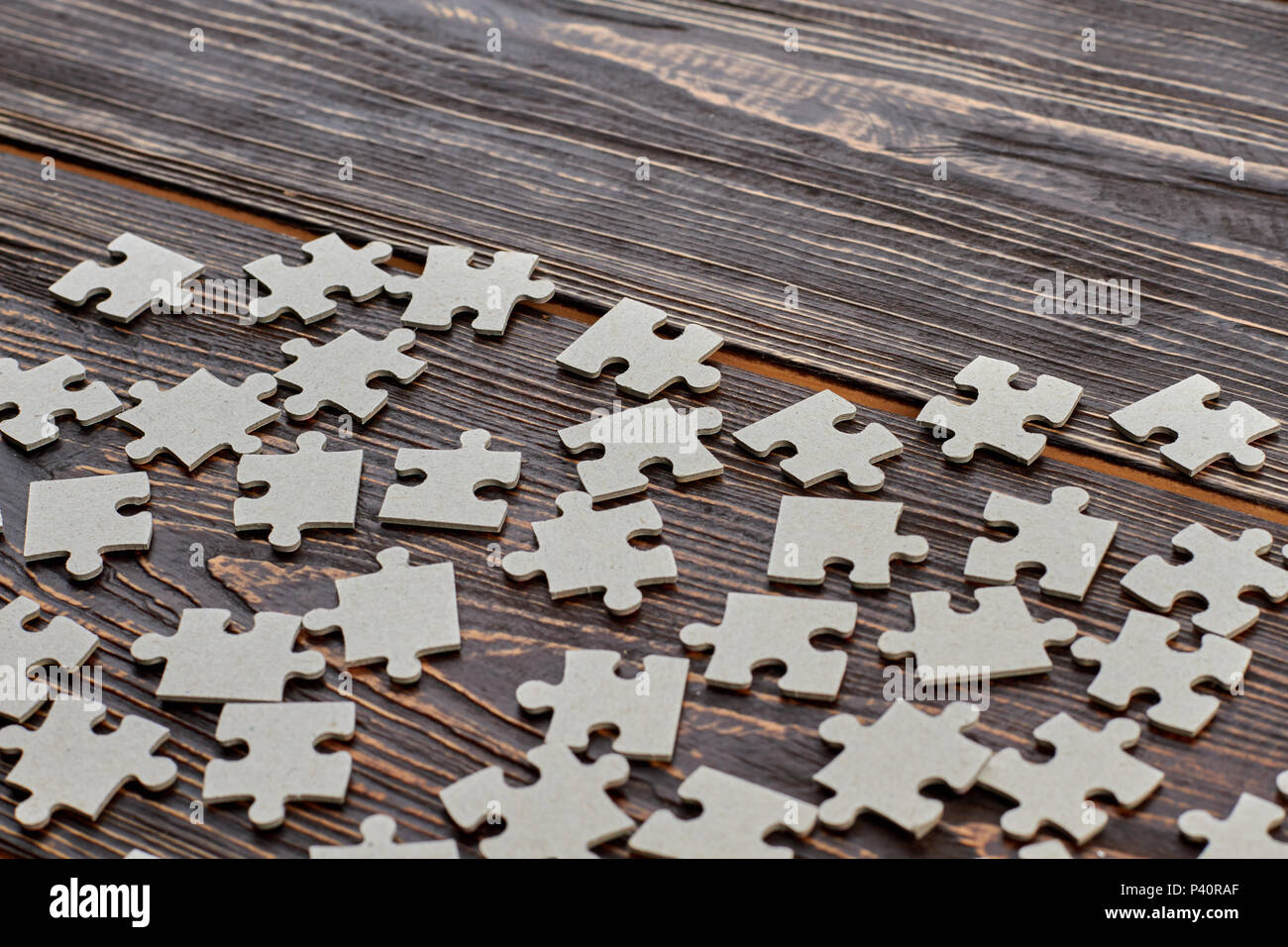 Grey cardboard puzzles on wooden background. Blank grey jigsaw puzzle