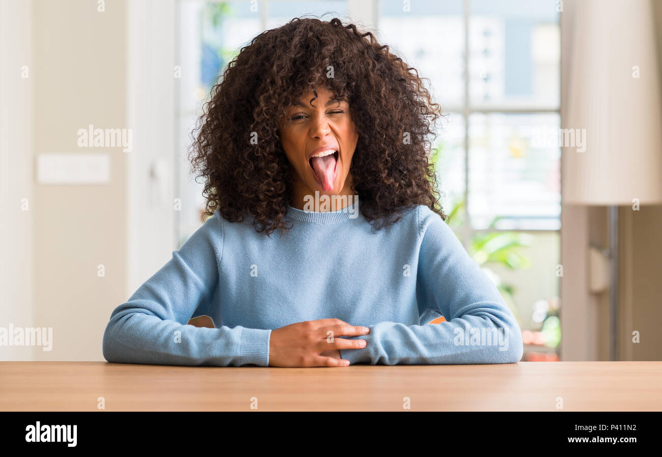 African american woman at home sticking tongue out happy with funny ...