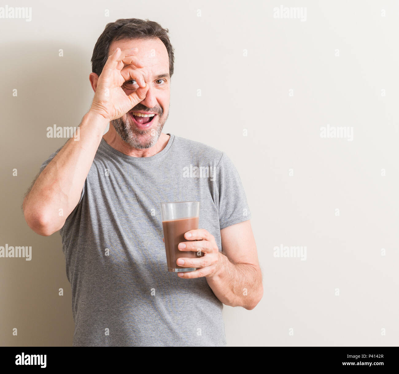 Senior man drinking chocolate milk shake with happy face smiling doing