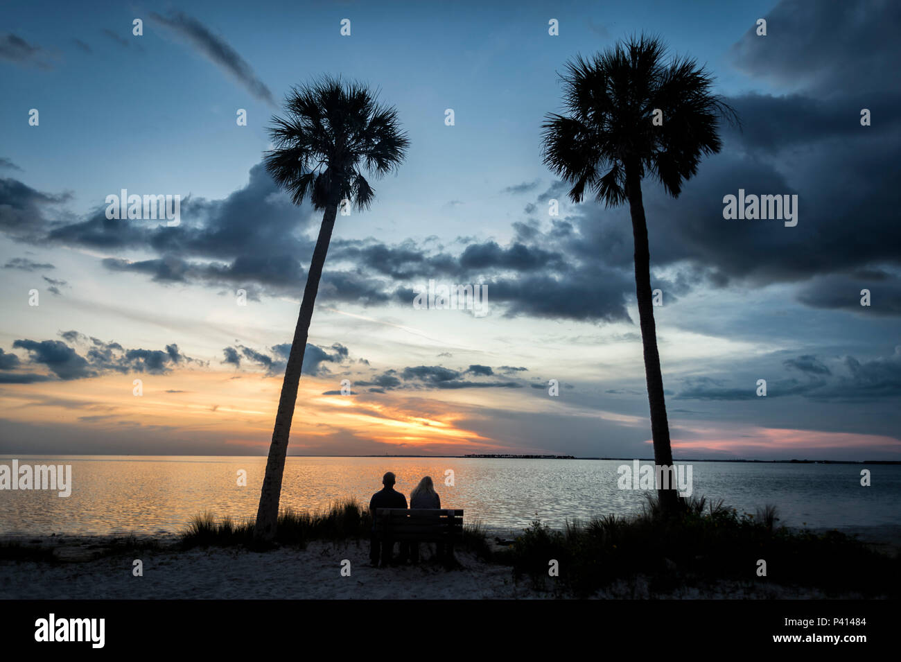 a couple sitting on a bench watching the sunset at Sunset Beach, Tarpon Springs, Florida, USA Stock Photo