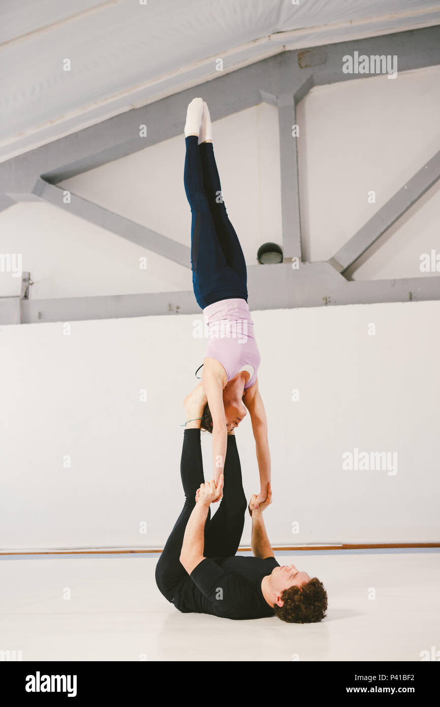 Figure De Gym Facile A 2 young Caucasian male and female couple practicing acrobatic yoga in a white  gym on mats. Loy HAND-TO-HAND, Skills Wind Mill, Position Type L-Bass, Dif  Stock Photo - Alamy