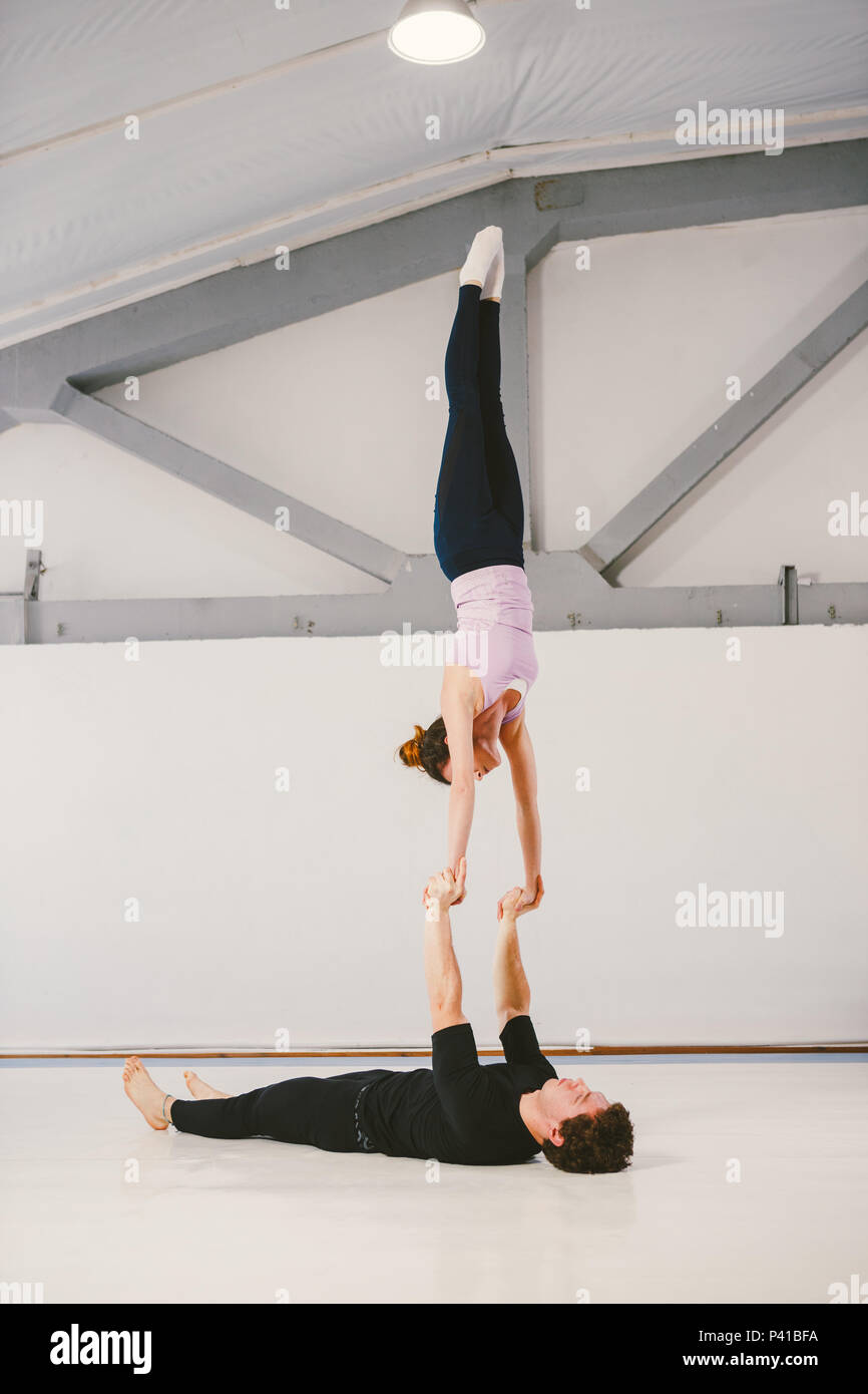 young Caucasian male and female couple practicing acrobatic yoga in a