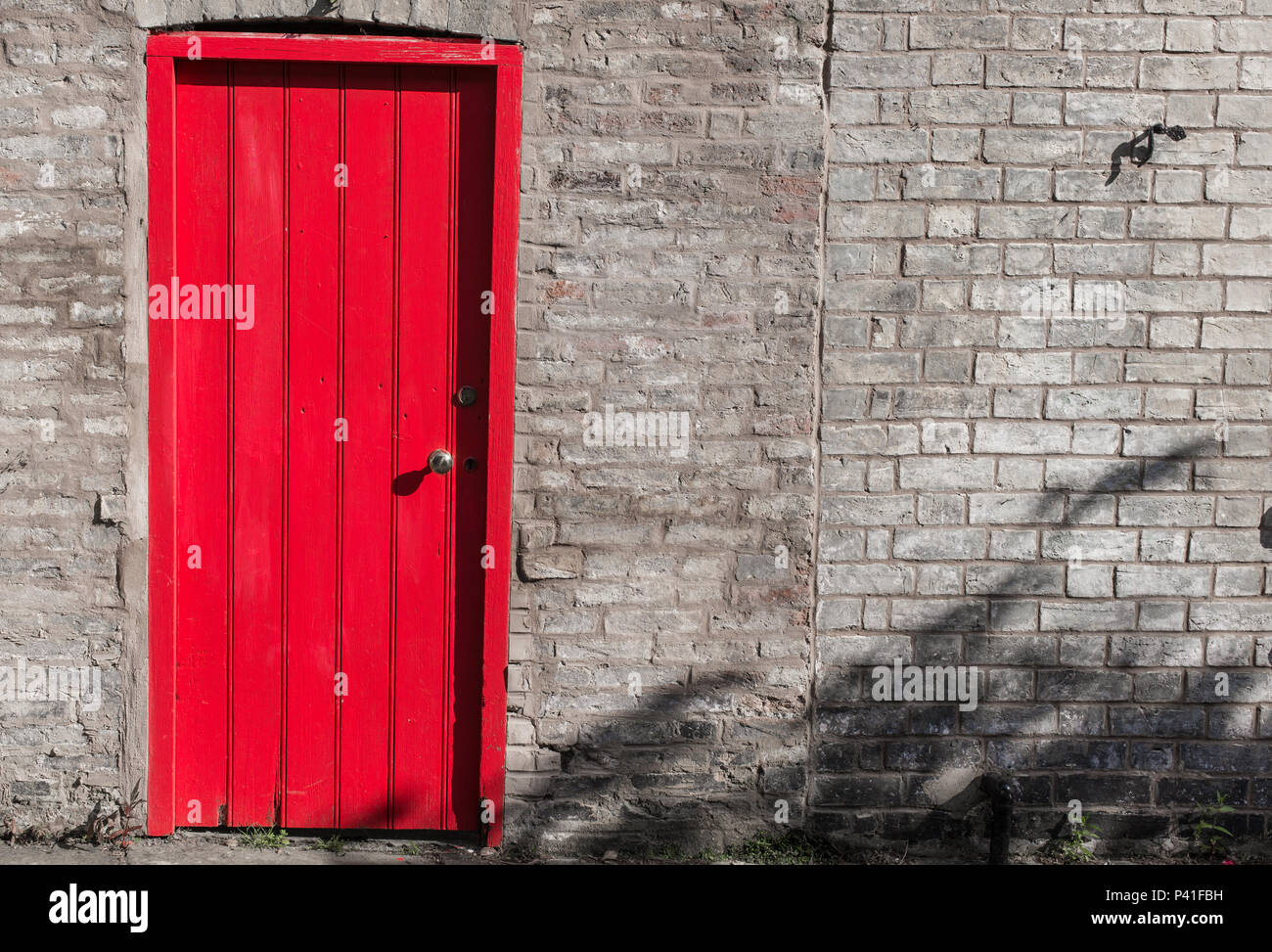 Closed wooden door bright red on a brick wall Stock Photo