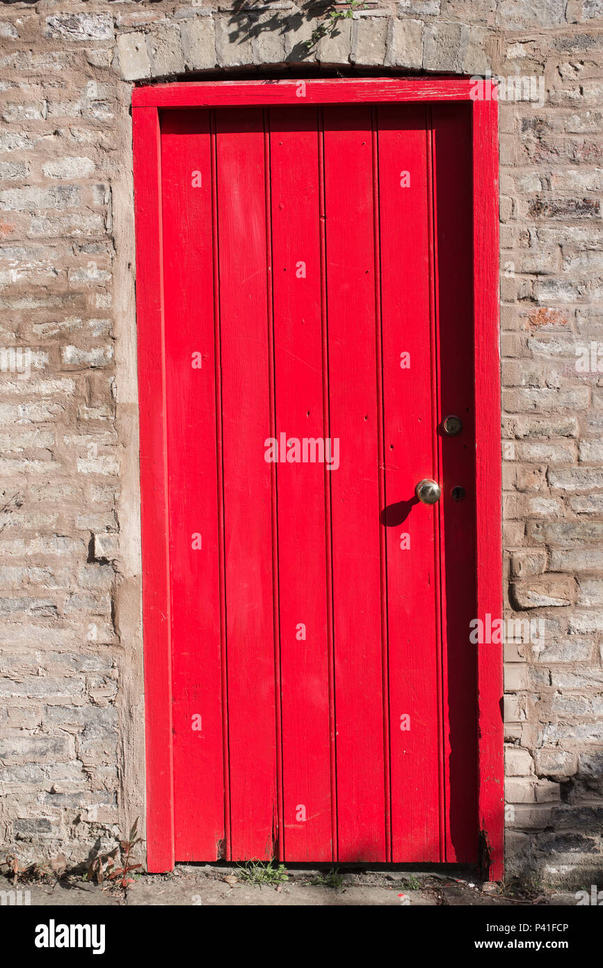 Closed wooden door bright red on a brick wall Stock Photo