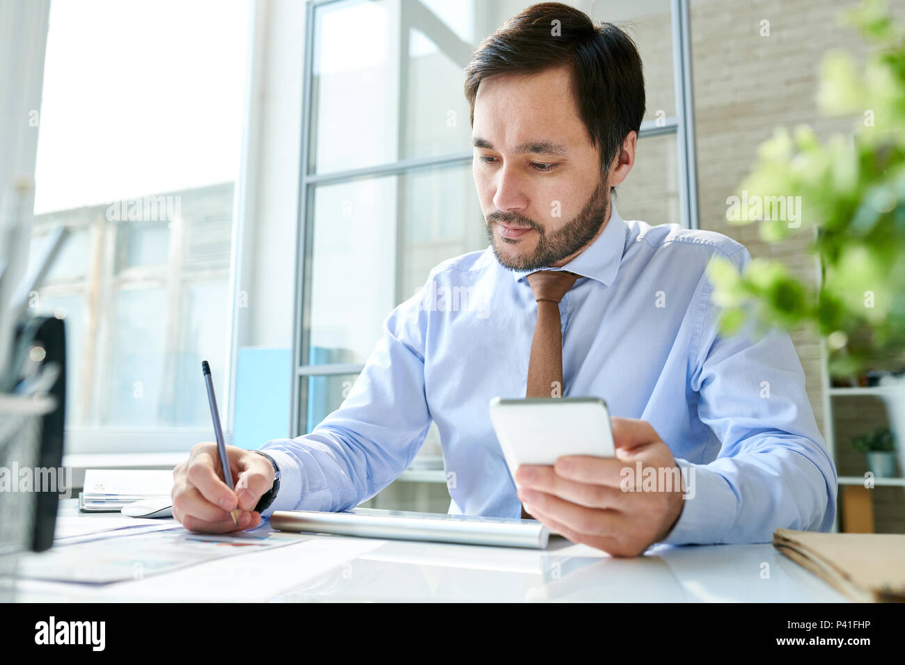 Employee working with smartphone in office Stock Photo