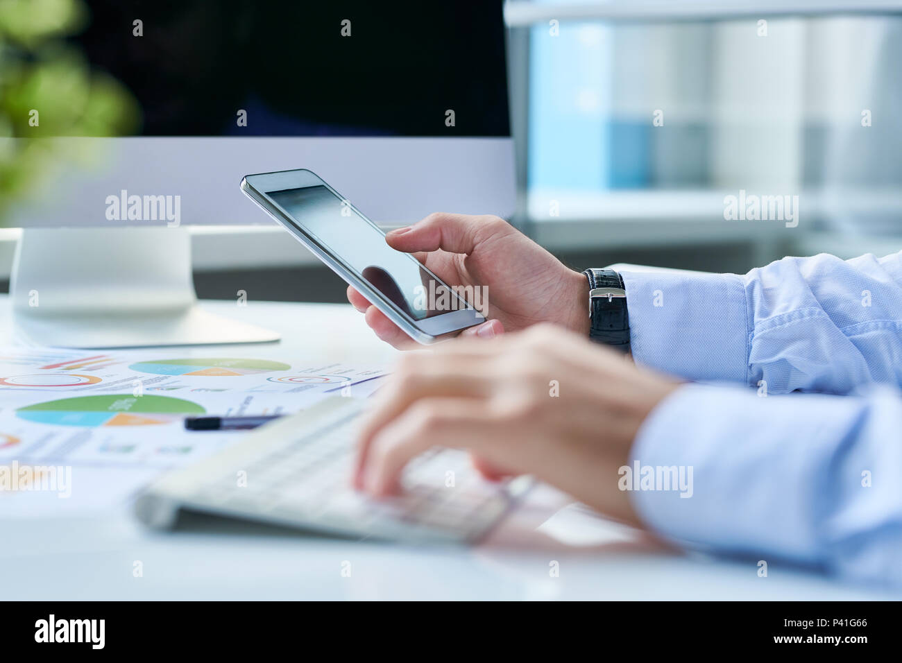 Crop entrepreneur with smartphone at workplace Stock Photo