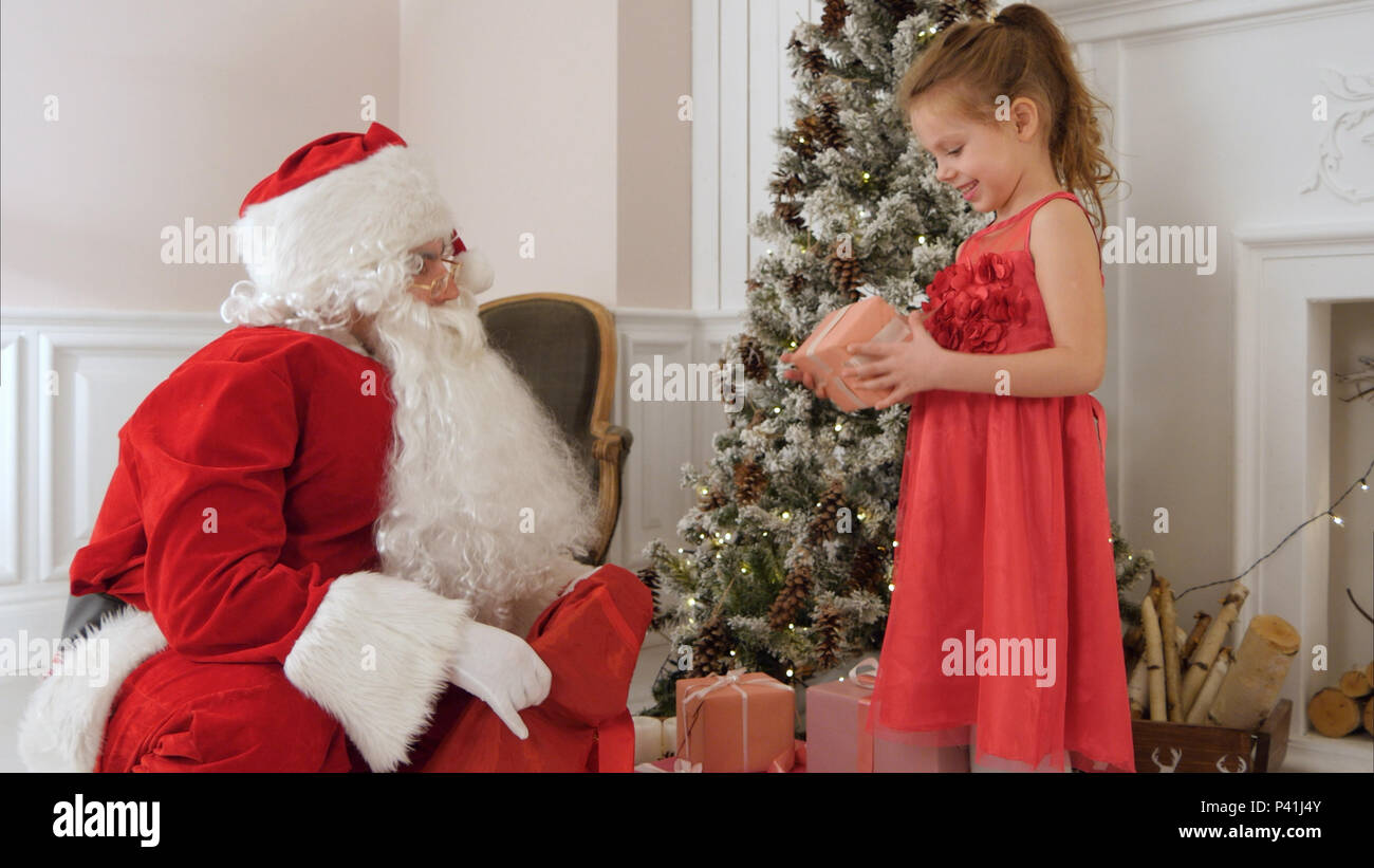 Santa Claus giving present to a surprised little girl Stock Photo - Alamy