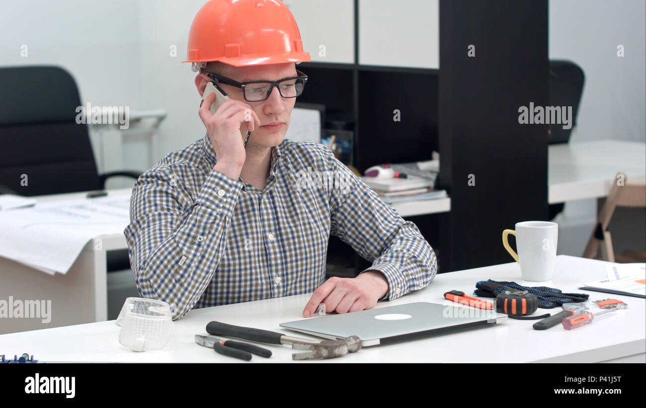 Young architect in helmet having important phone call Stock Photo