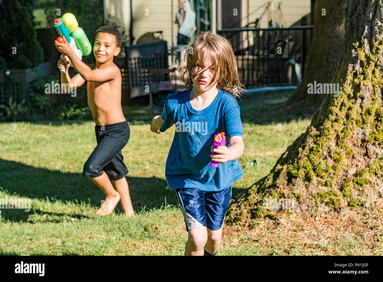 Keeping cool, summer fun,. Kids have friendly backyard water fight. Stock Photo