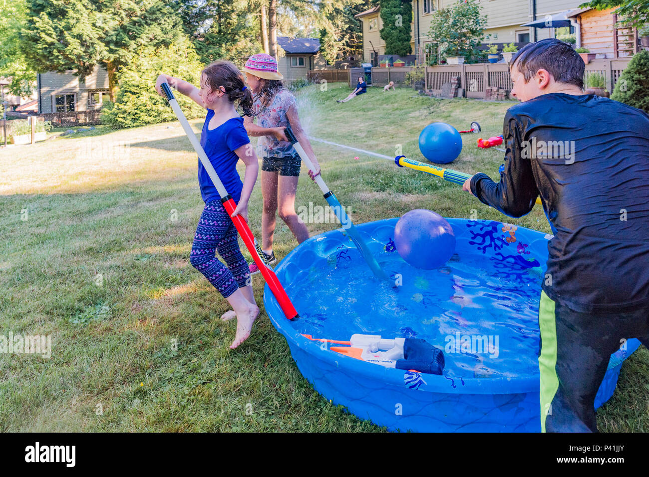 Keeping cool, summer fun,. Kids have friendly backyard water fight. Stock Photo