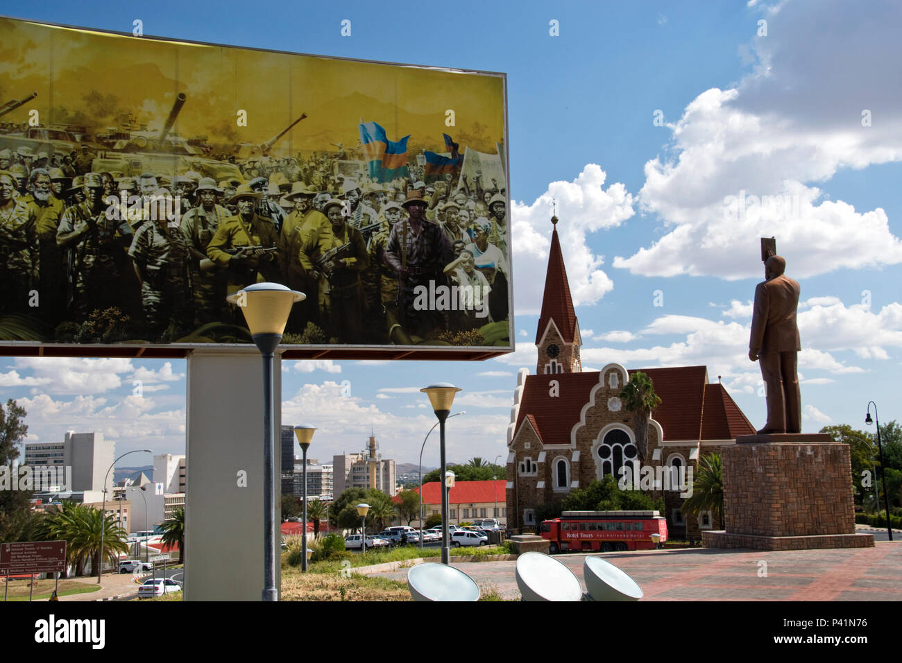 Statue of Sam Nujoma, first president of Namibia, stands by a revolutionary themed billboard with Christ Church in background, Windhoek, Namibia. Stock Photo