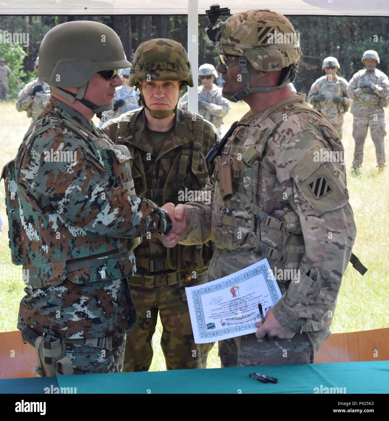 Polish Brig. Gen. Dariusz Gorniak, the commander of the Polish 10th Mechanized Brigade and the Land Forces Commander at Drawsko Pomorskie for Anakonda 16, looks on as Col. Phil Brooks, the commander for 1st Armored Brigade Combat Team, 3rd Infantry Division, shakes hands with a Soldier from the Former Yugoslav Republic of Macedonia after signing the authority agreement marking the official start of Exercise Anakonda 16 at Drawsko Pomorskie, Poland June 6. Stock Photo