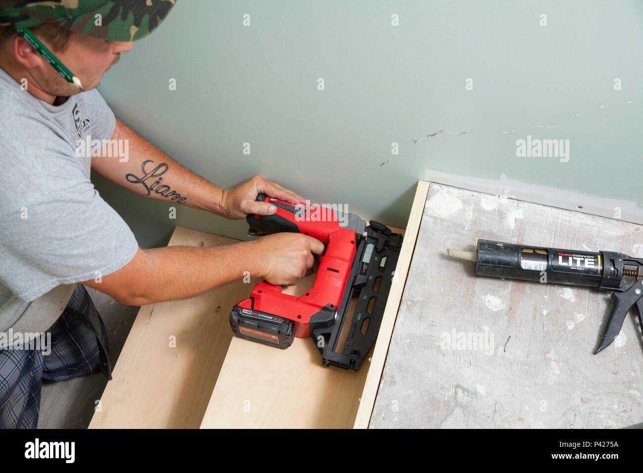 A construction worker using a nail gun for stairs installation in