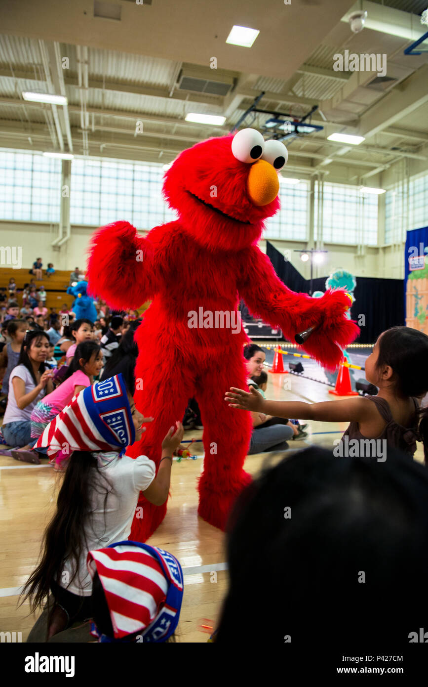 A military dependent from Travis Air Force Base, Calif., is about to get a  hug from Elmo during the performance of the Sesame Street USO Experience  for Military Families at the base