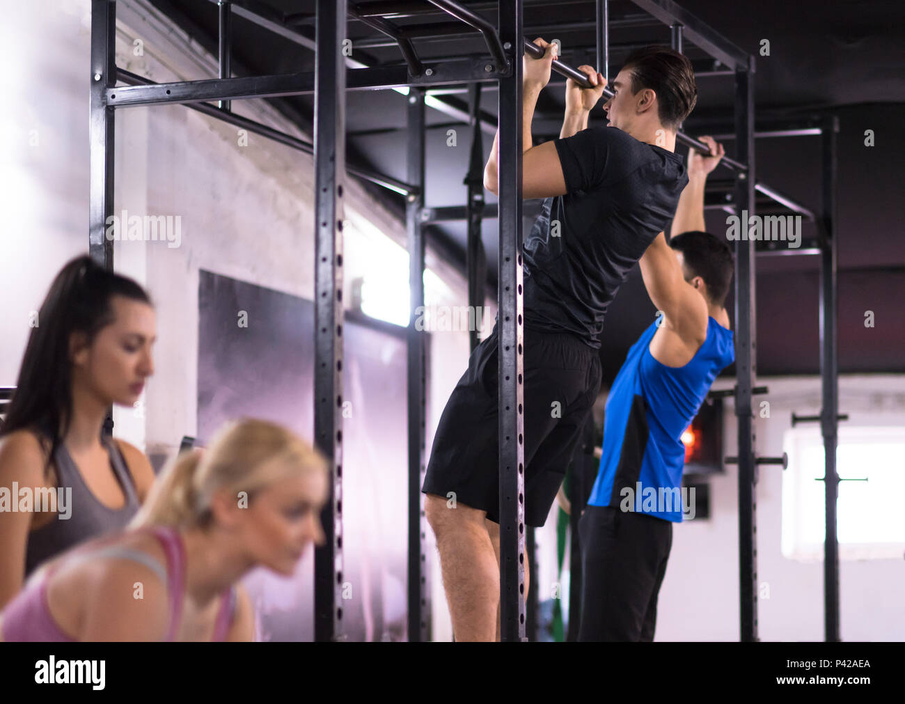 group of young muscular athletes doing pull ups on the horizontal bar ...