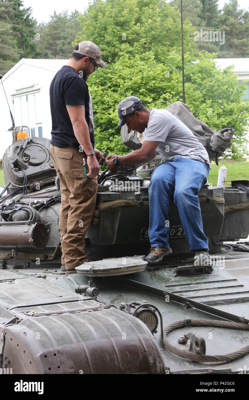 Multiple Integrated Laser Engagement Systems (MILES) specialists attach MILES components on an M-84 main battle tank of 45th Center for Tracked Combat Vehicles (CGBV) during Swift Response 16 training exercise at the Hohenfels Training Area, a part of the Joint Multinational Readiness Center, in Hohenfels, Germany, Jun. 8, 2016. Exercise Swift Response is one of the premier military crisis response training events for multi-national airborne forces in the world. The exercise is designed to enhance the readiness of the combat core of the U.S. Global Response Force – currently the 82nd Airborne  Stock Photo