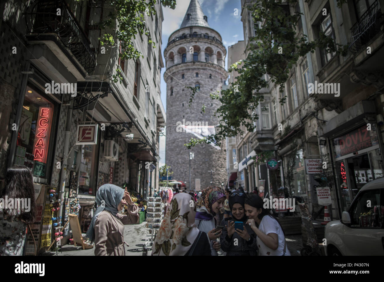 Istanbul, Turkey. 20th June, 2018. Young Turkish women smiles as they look on a cellphone backdropped by the Galata Tower in Istanbul, Turkey, 20 June 2018. The country will hold snap elections on June 24th. Credit: Oliver Weiken/dpa/Alamy Live News Stock Photo