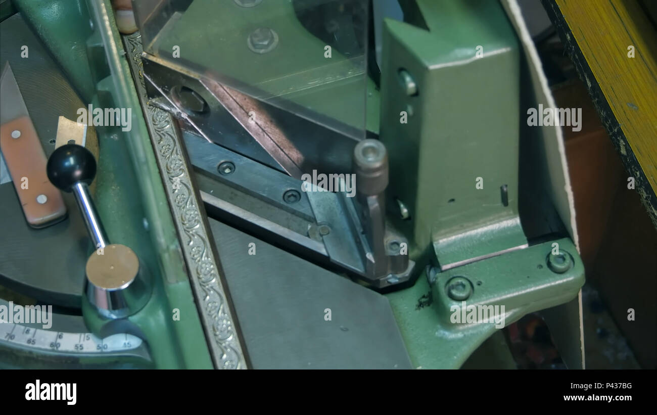 Craftsman working on frame in frame shop, using machine Stock Photo