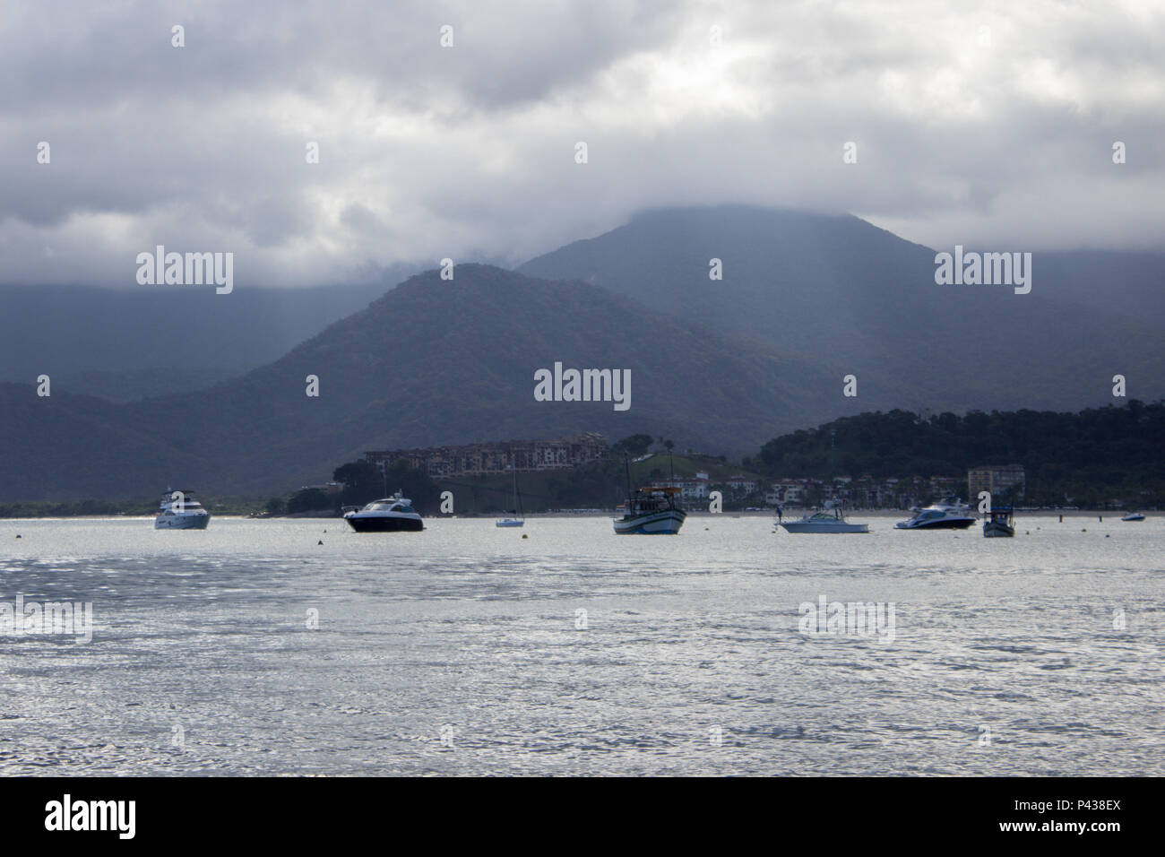 Costa de ilha com barcos navegando no mar com montanhas ao fundo em Ubatuba, SP, Brasil. Stock Photo