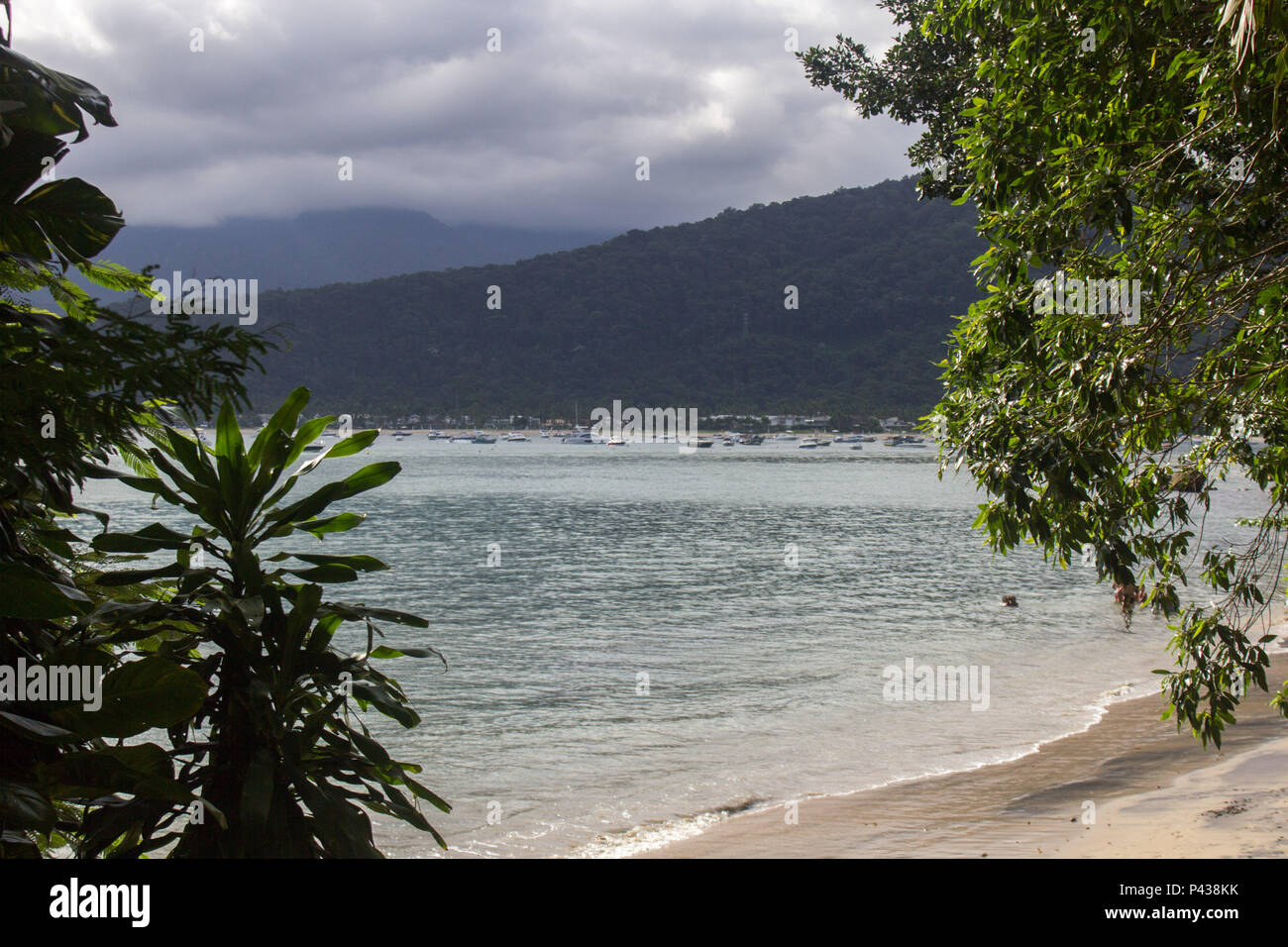 Praia com barcos navegando no mar com montanha ao fundo em Ubatuba, SP, Brasil. Stock Photo