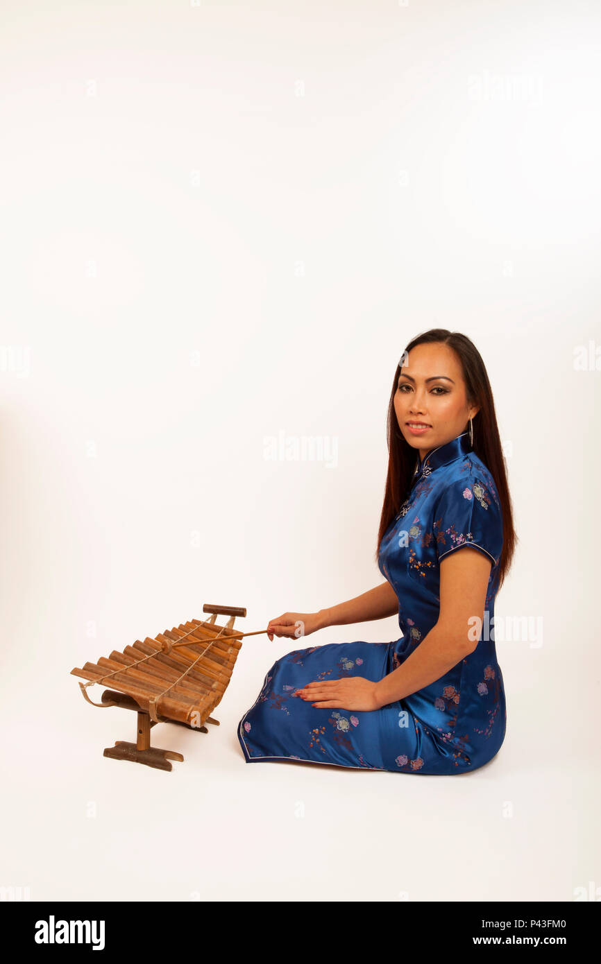 Chinese lady playing a bamboo Xylophone with a wooden beater