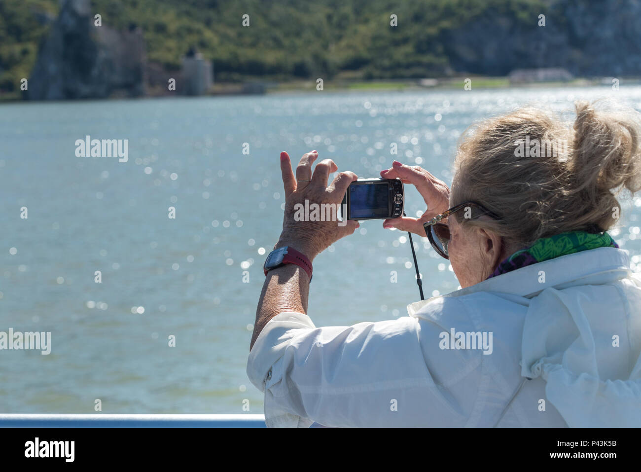 Woman taking picture of Danube River with digital camera, Coronini, Caras-Severin County, Romania Stock Photo