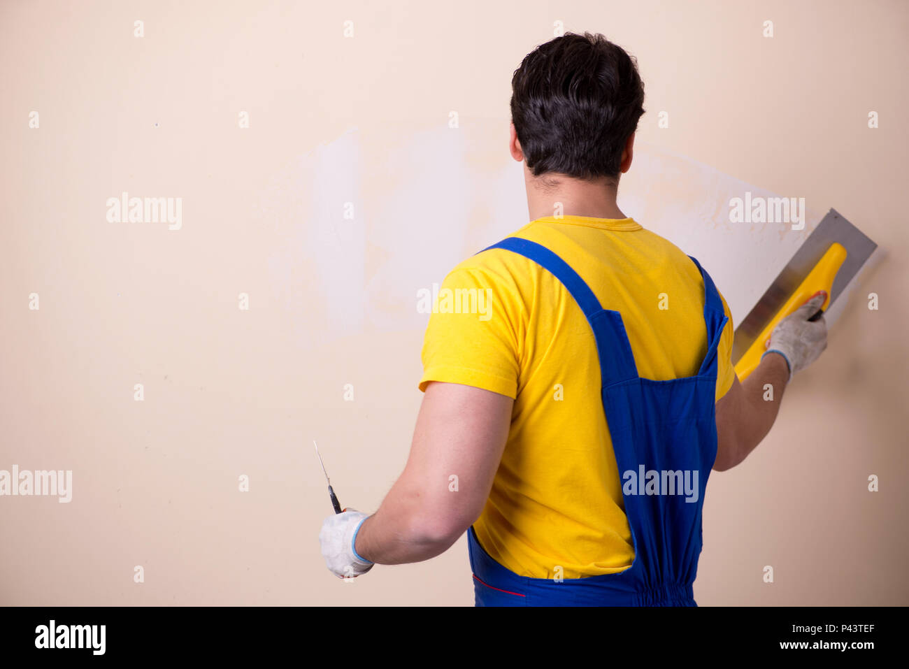 Young contractor employee applying plaster on wall Stock Photo