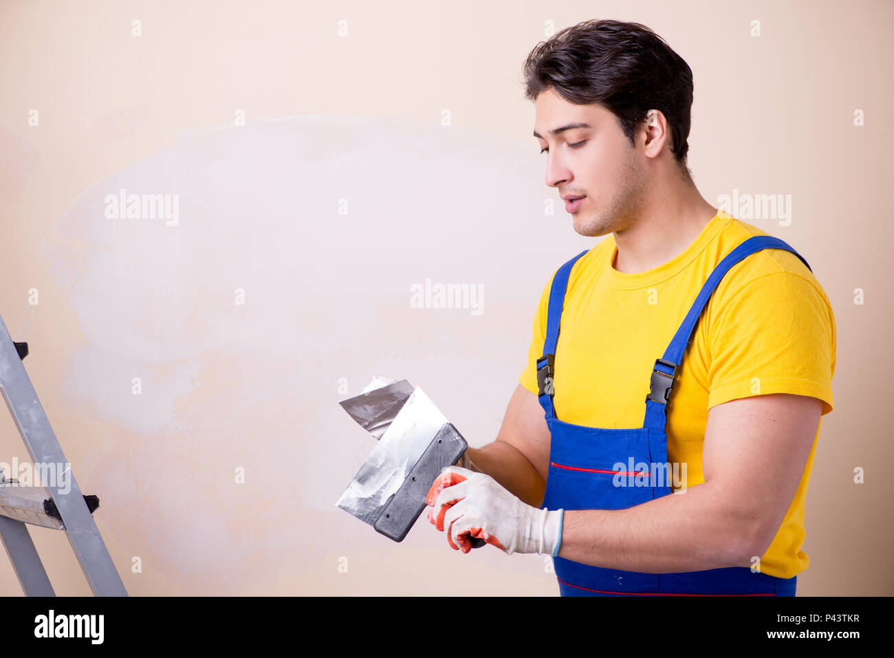 Young contractor employee applying plaster on wall Stock Photo