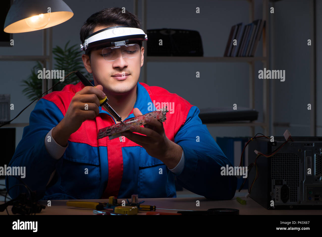 Computer specialist repairing PC late at night Stock Photo - Alamy