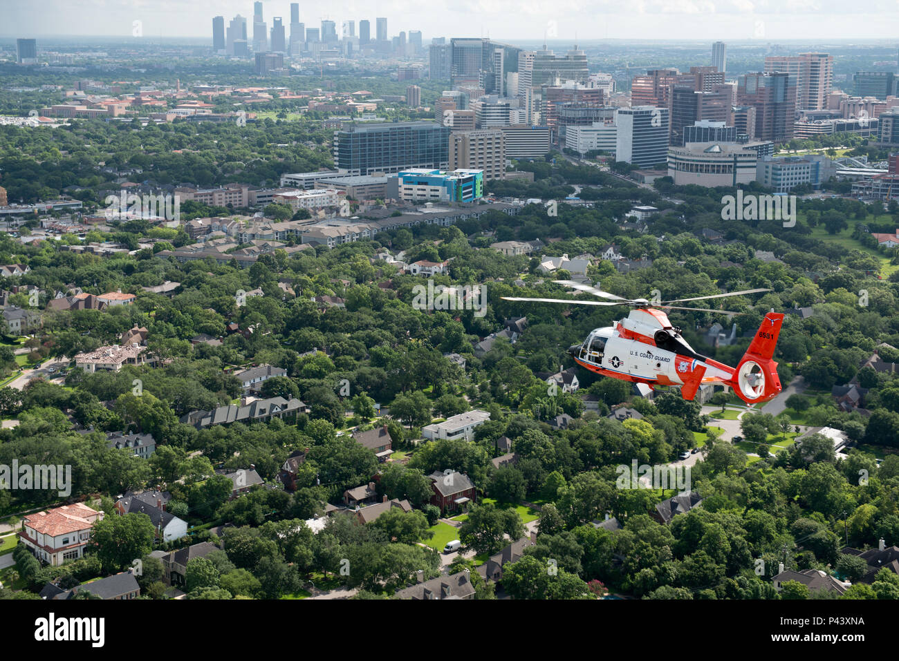 As part of the 100 years of Coast Guard aviation, the Air Station Houston centennial MH-65 Dolphin helicopter participated in a form flight over Houston, June 10, 2016. Form Flights offer a unique opportunity to see Coast Guard aircraft from a different point-of-view. U.S. Coast Guard photo by Petty Officer 3rd Class Dustin R. Williams Stock Photo
