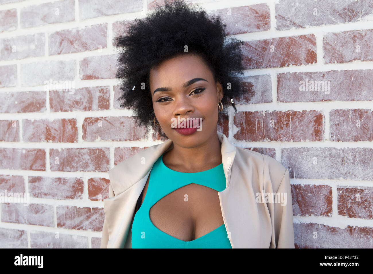 An african female model poses in a cut out dress against a white washed ...