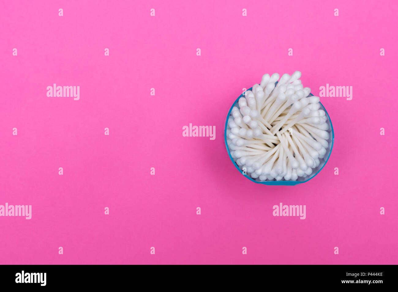 Cotton swabs in plastic jar on pink background. Single use plastic