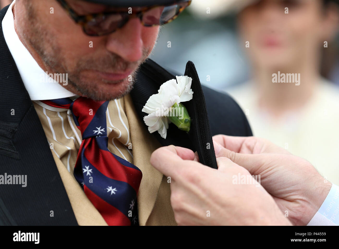 A racegoer has a corsage attached to his lapel during day two of Royal Ascot at Ascot Racecourse. Stock Photo