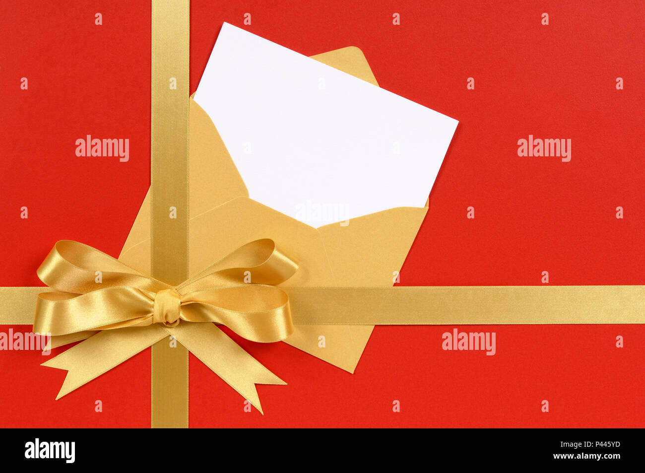Red and gold Christmas gift with blank invitation or greetings card. Stock Photo