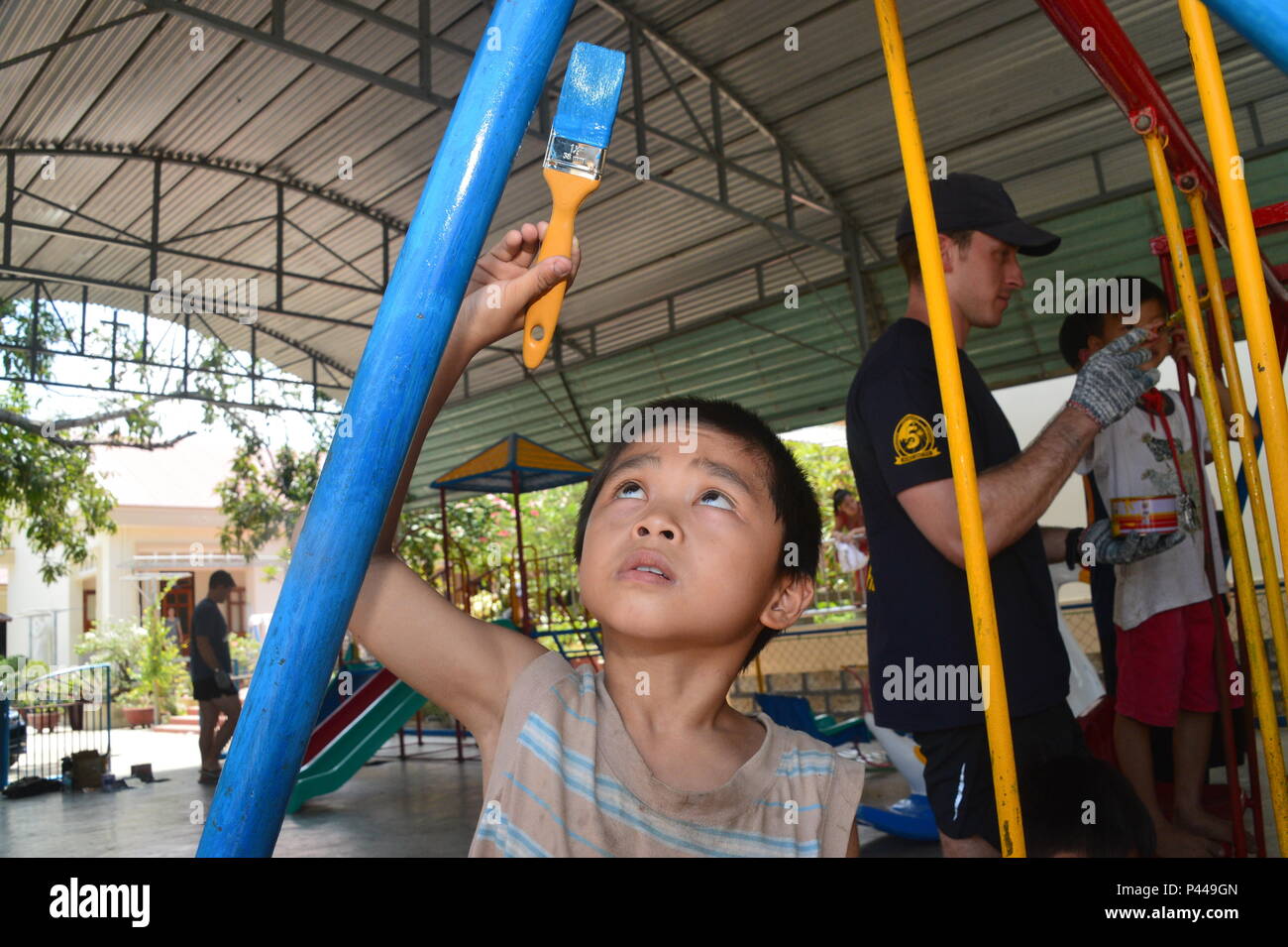 Children living at the Mai Am Anh Dao Orphanage repaint a playground with Sailors assigned to Explosive Ordnance Disposal Mobile Unit (EODMU) 5 as part of a community partnership event in Ninh Hoa, Vietnam, June 11, 2016. The exercise provides an opportunity for Vietnam and U.S. forces to continue strengthening relationships as EODMU5’s Sailors volunteered their time to help plant trees, fix wiring and electronics, and repaint a playground. The Mai Am Anh Dao Orphanage relies almost entirely on donations, which go to the purchasing of food for the orphans, general upkeep of the orphanage, and  Stock Photo