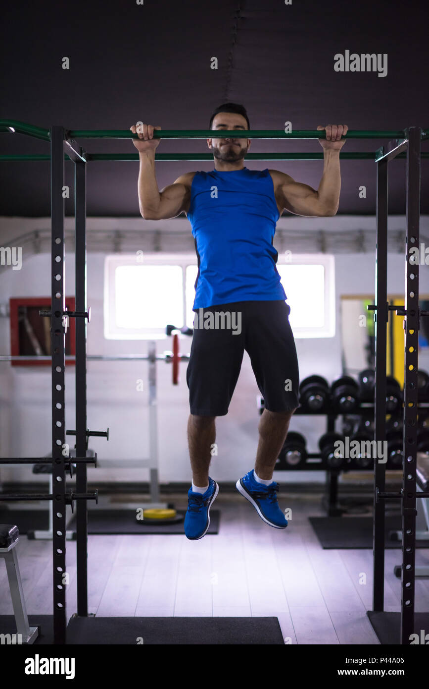 young muscular man doing pull ups on the horizontal bar as part of ...
