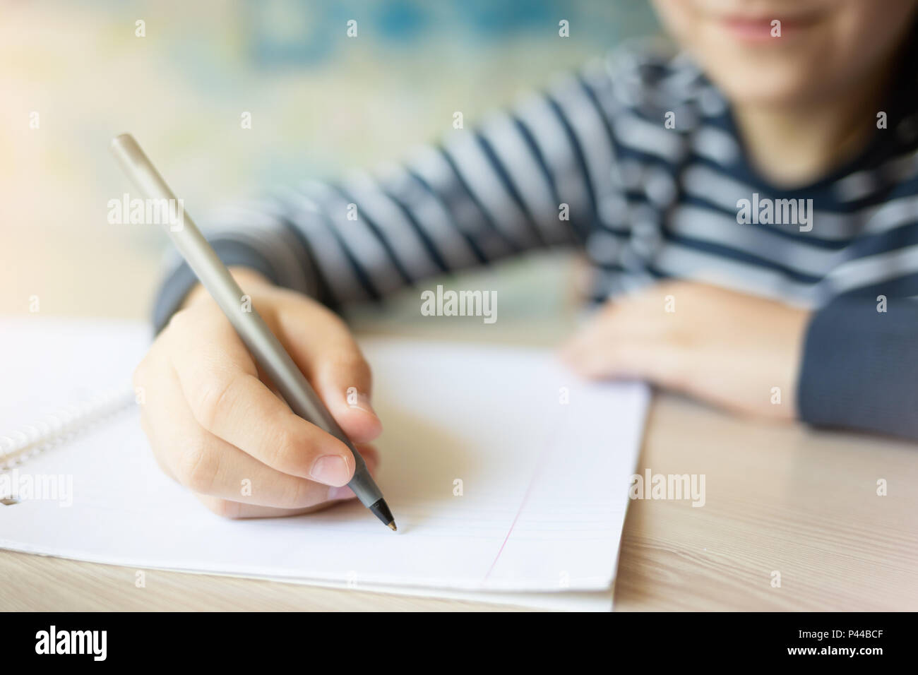 Kid writing in notebook and smiling. Close up. Stock Photo