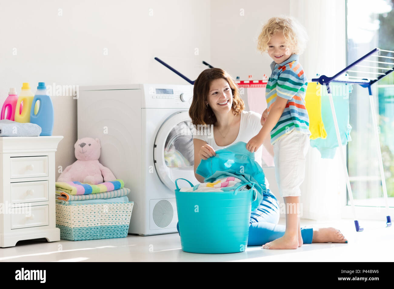 Mother and kids in laundry room with washing machine or tumble dryer. Family chores. Modern