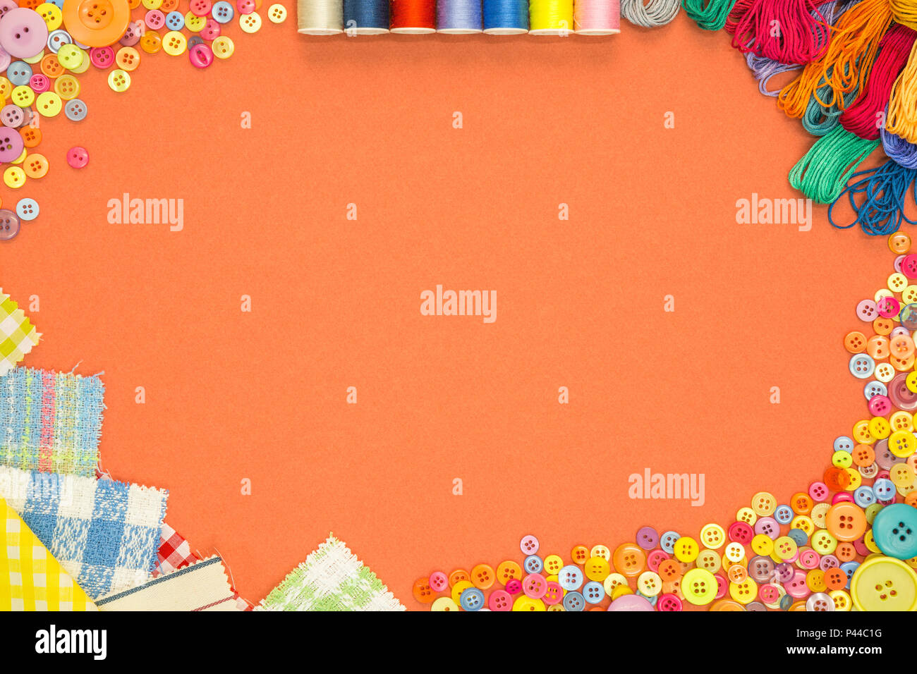 Arts and Crafts background with material and buttons on an orange textured paper background with blank copy space. Stock Photo